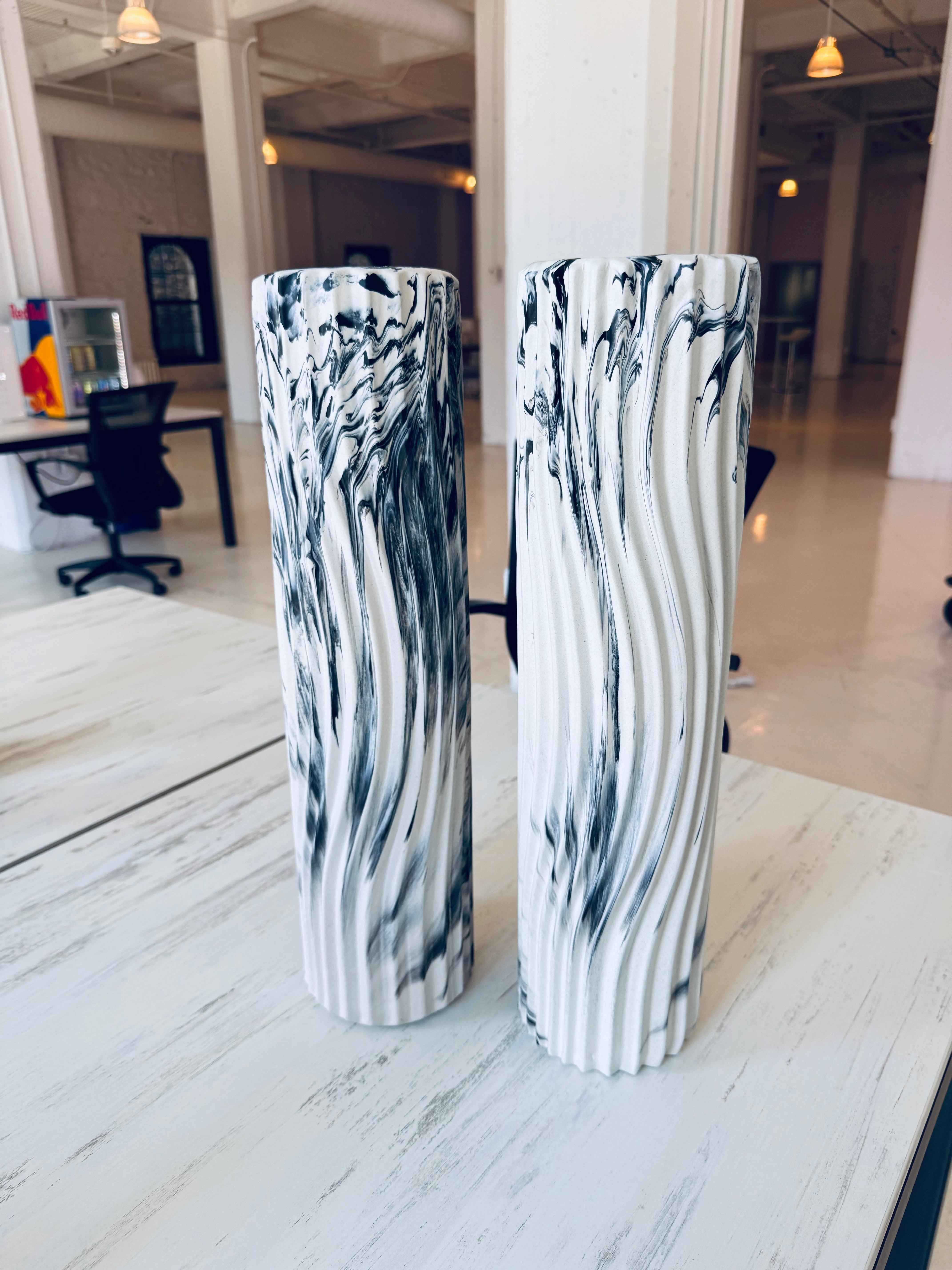 Image of two black and white foam rollers on top of a white and gray patterned desk table